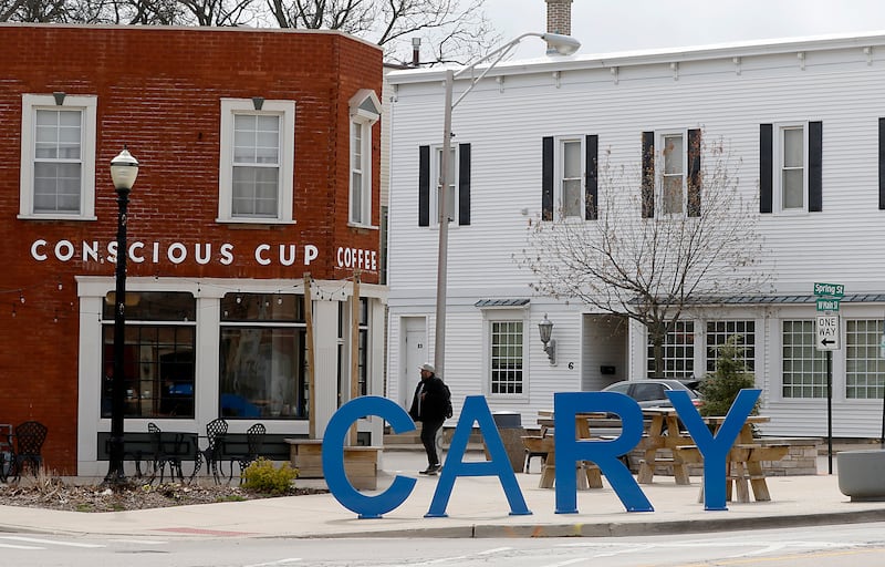 A man walks past the Cary sign in near the intersection of West Main Street and Spring Street in Cary on Tuesday, April 25, 2023. The Village of Cary is considering a new tax increment financing district in its downtown corridor to help spur new development in the oldest part of its town.