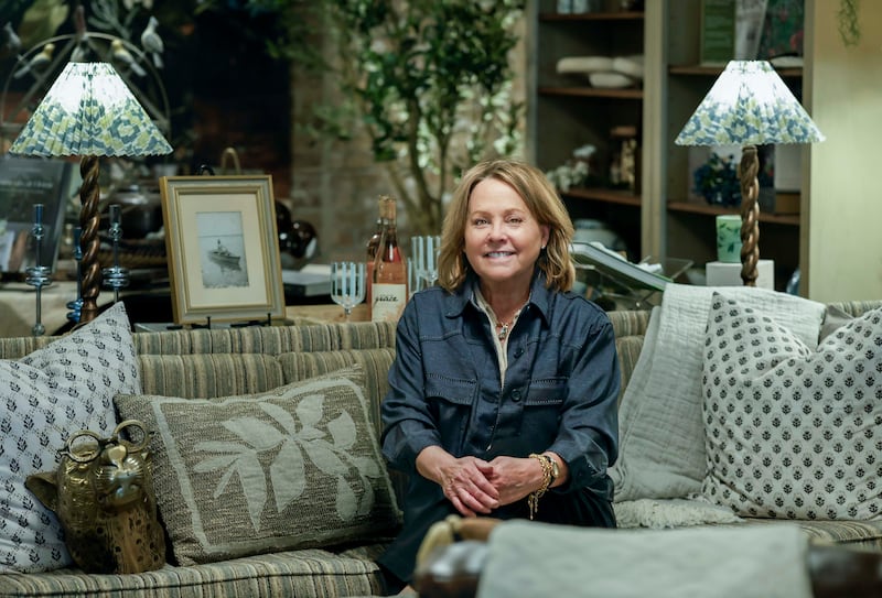 Fran Rouse, seated on a vintage sofa near a painting of her mother, in her newly opened Stonehouse store in downtown Wheaton.