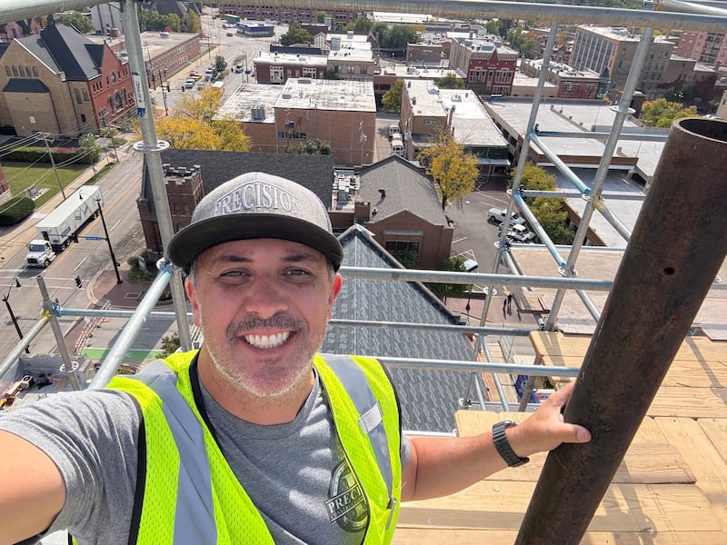 McHenry's Jeremy Bates stops for a selfie on top of Elgin's First United Methodist Church on Friday, Oct. 17, 2025. The McHenry man leads crews restoring churches around the country damaged by weather.