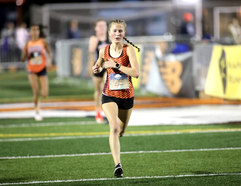 Batavia’s Avery Hacker comes in third place in the varsity girls race during the Naperville North Twilight Cross Country Invitational on Wednesday, Oct. 9, 2024 in Naperville.