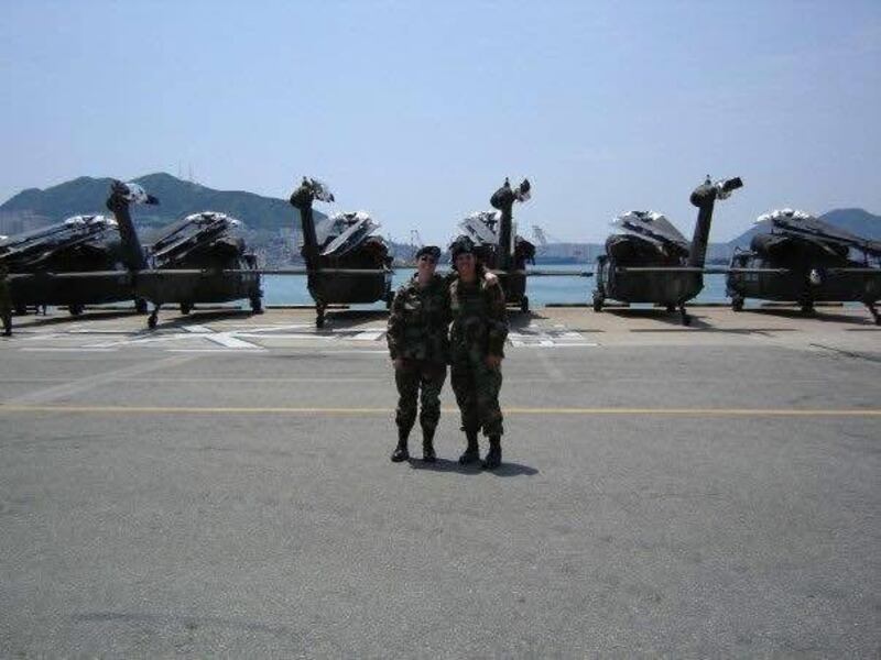 Tara Phelps with a colleague in front of a series helicopters being shipped from South Korea back to the United States.