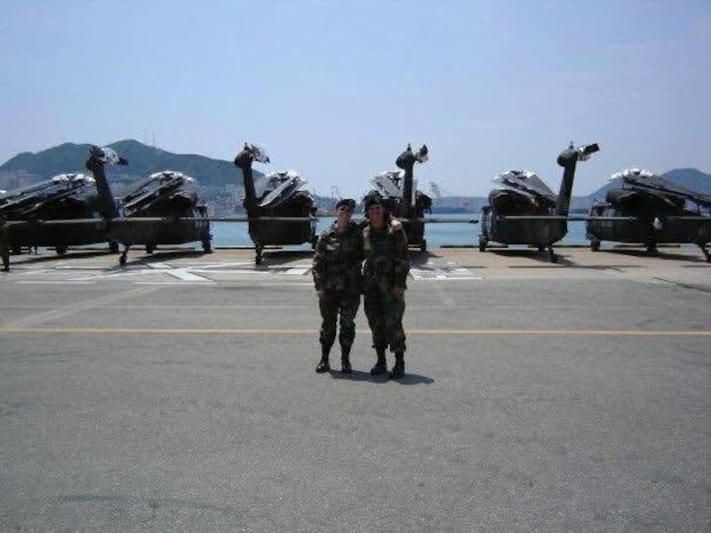 Tara Phelps with a colleague in front of a series helicopters being shipped from South Korea back to the United States.