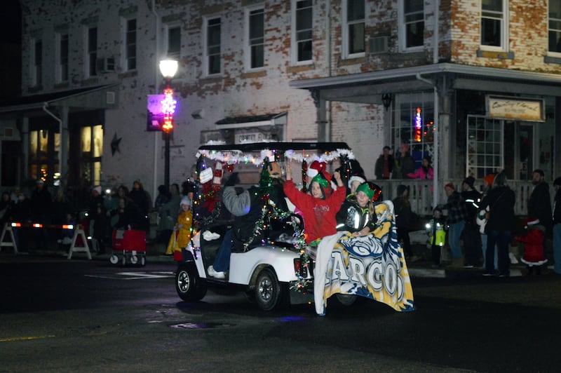 Kids wave from the back of a decked-out golf cart that participated in the Polo Christmas Festival's first ever Parade of Lights on Saturday, Dec. 2, 2023.