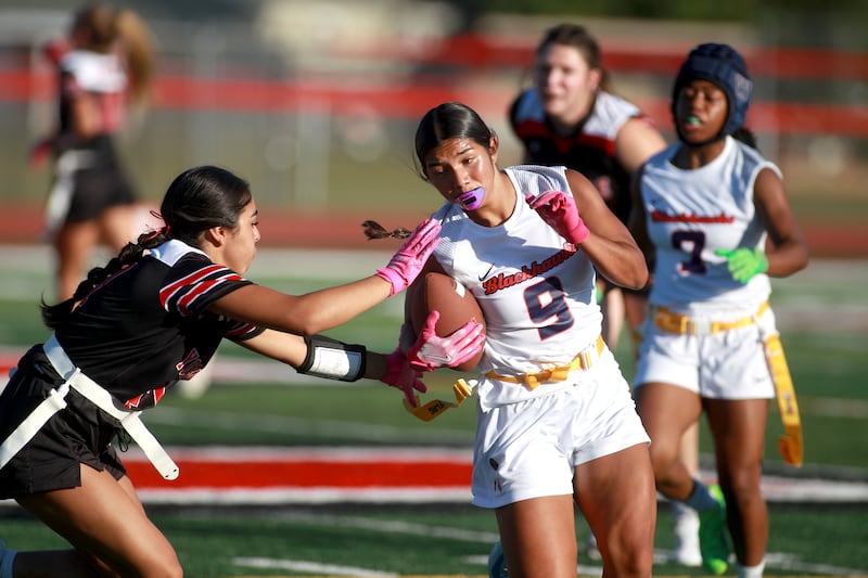 West Aurora’s Sarahi Carlos runs with the ball as Yorkville’s Bella Esquivel goes for her flag during a flag football game Wednesday, Sept. 4, 2024 in Yorkville.