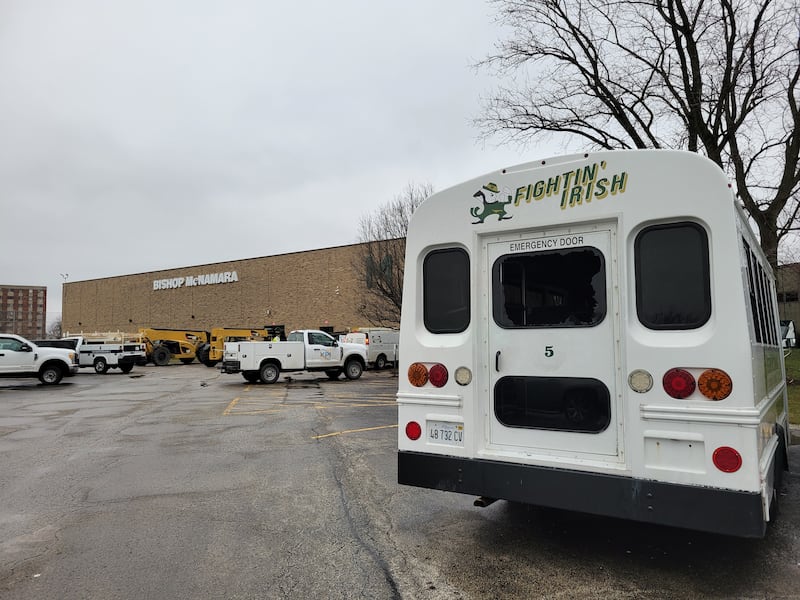 A bus has a broken window and contractors work to repair damage to Bishop McNamara Catholic School's Kankakee site on Wednesday, March 11, 2026, following a Tuesday evening storm.