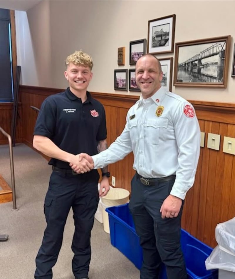 Jackson Novak (left) is sworn in as a probationary firefighter with the Ottawa Fire Department as Deputy Chief Mike Mills shakes his hand during a ceremony at Ottawa City Hall.