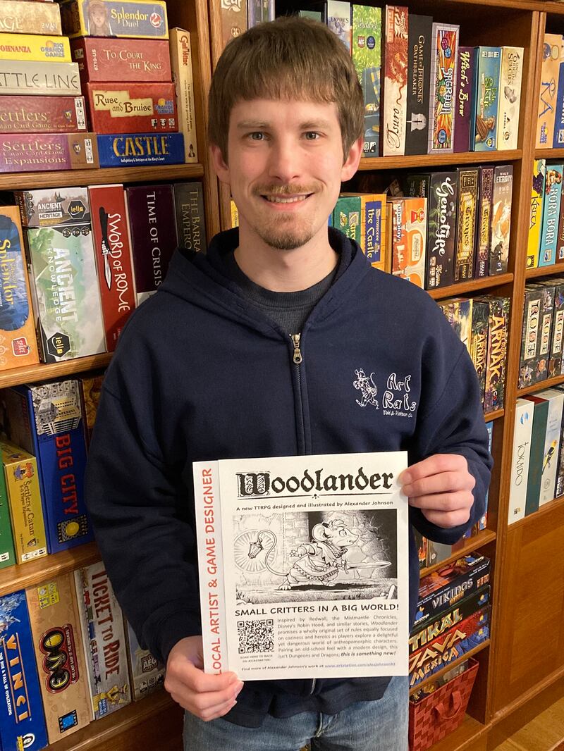 Crystal Lake South graduate Alexander Johnson with flyer for his soon-to-be-published roleplaying game Woodlander.