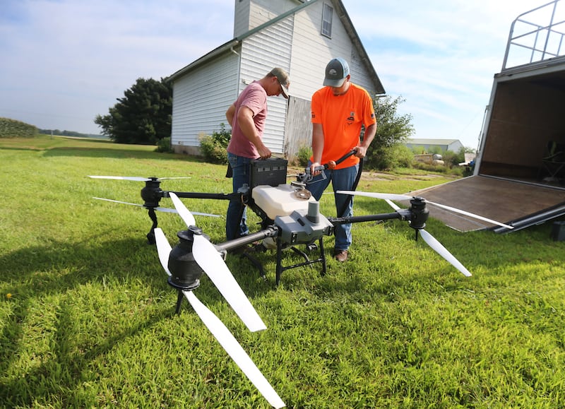 Tyce Barkman of Sweetwater Technologies inserts a new battery into a DJ AGRAS T40 drone as Brodie Jagers fills DRONEZONE, a product containing fungicide, insecticide, and herbicide applications into a 18.5 gallon tank on a farm on Wednesday, Aug. 6, 2025 outside of Amboy. New hi-tech drone technology throughtout Northern Illinois is providing more accurate and precise aerial application then the average crop duster. The spray airplane hasn’t made it’s final approach yet but there's a possibility it may disappear in our lifetimes.