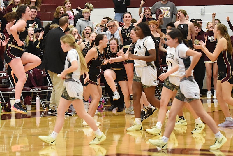 The Mt. Carmel girls basketball team celebrates its first-ever trip to the IHSA State Finals as Bishop McNamara players leave the floor in the foreground following the Golden Aces' 61-42 win in the Class 2A Tolono Unity Super-Sectional Monday, March 3, 2025.