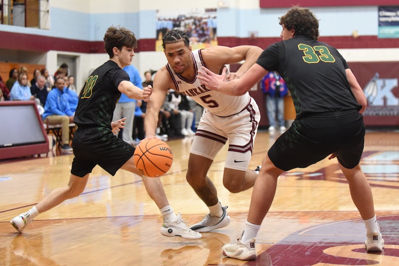 Kankakee's EJ Hazelett, center, splits Waubonsie Valley's Evan Malushi, left, and Kyler Payne during a game at Kankakee Monday, Feb. 16, 2026.