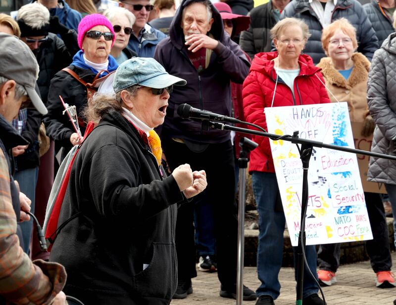 Cynthia de Seife, coordinator of REACT, speaks to the hundreds of people assembled Saturday, April 5, 2025, for a Hands Off! rally at Memorial Park on the corner of First Street and Lincoln Highway in DeKalb. The group gathered to protest against various policies of President Donald Trump and his administration.