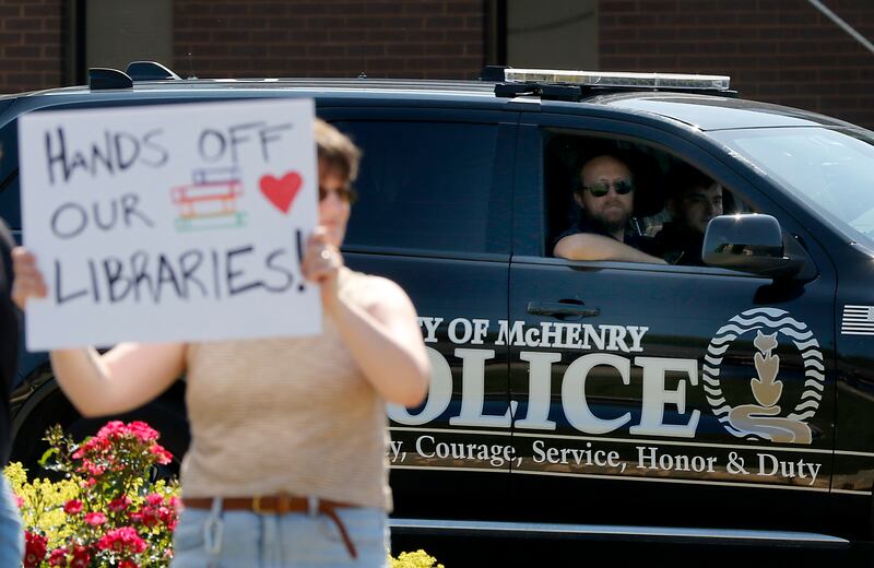 A McHenry police officer watches as people protest along Route 31 in front of the McHenry Public Library on Friday, June 20, 2025, during a Save Our Libraries Protest hosted by Indivisible McHenry County to draw attention to cuts to the nation’s libraries by the Trump administration.