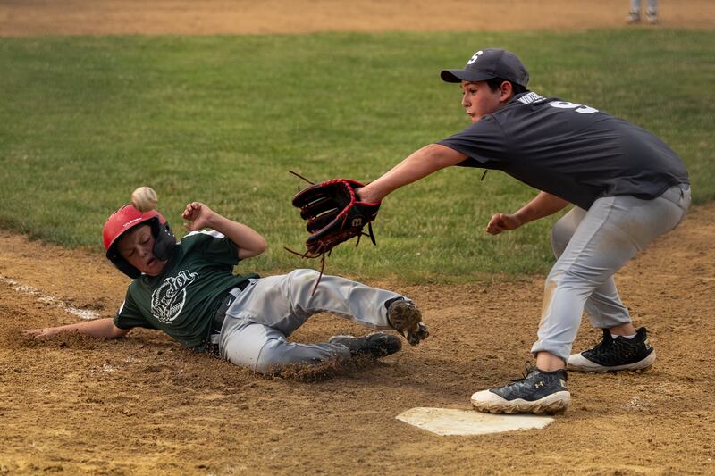 Hatzer & Sons baserunner Ben Brown slides into home plate after a wild pitch as Elliott Volkman (9) of Winterrowd Funeral covers Wednesday, June 25, 2025, at Southside Park in Streator.