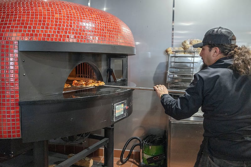 Cory Canas pulls a pizza out of the brick oven Thursday, March 19, 2026, at Artisan Oven in Sterling.