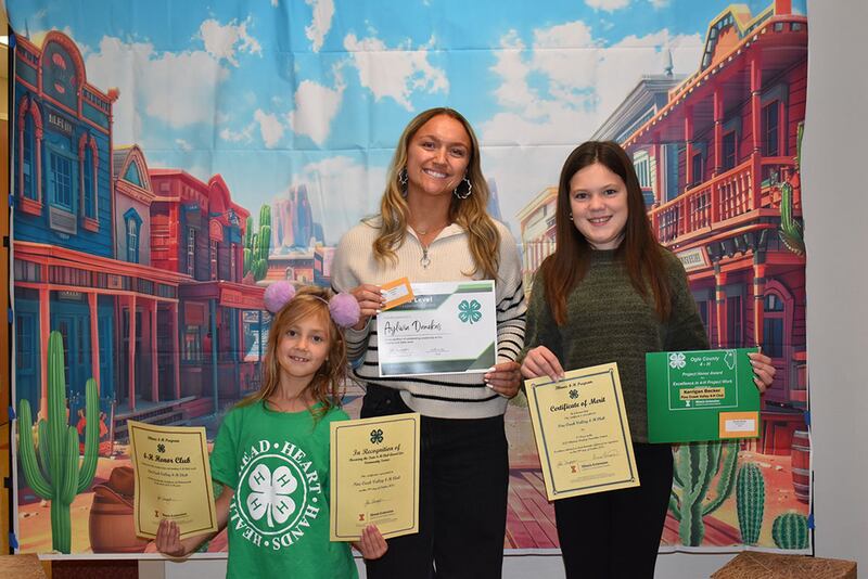 Members of the Pine Creek Valley 4-H Club (Polo) hold up the awards their club received: 4-H Honor Club, Illinois State 4-H Club Award, and Second Place Window Display Contest Award. From left to right: June Robertson, Aylivia Danekas and Kerrigan Becker.