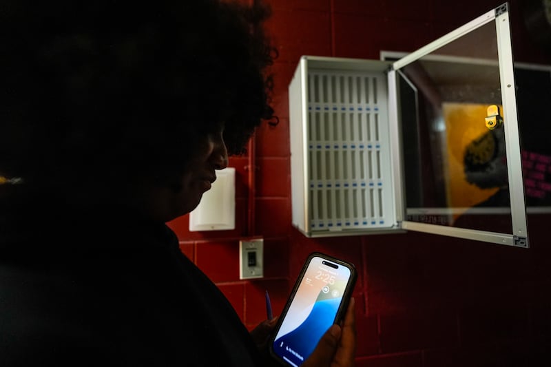 Student Audreanna Johnson views her cell phone near a cell phone locker at Ronald McNair Sr. High School, Thursday, Aug. 7, 2025, in Atlanta. (AP Photo/Mike Stewart)