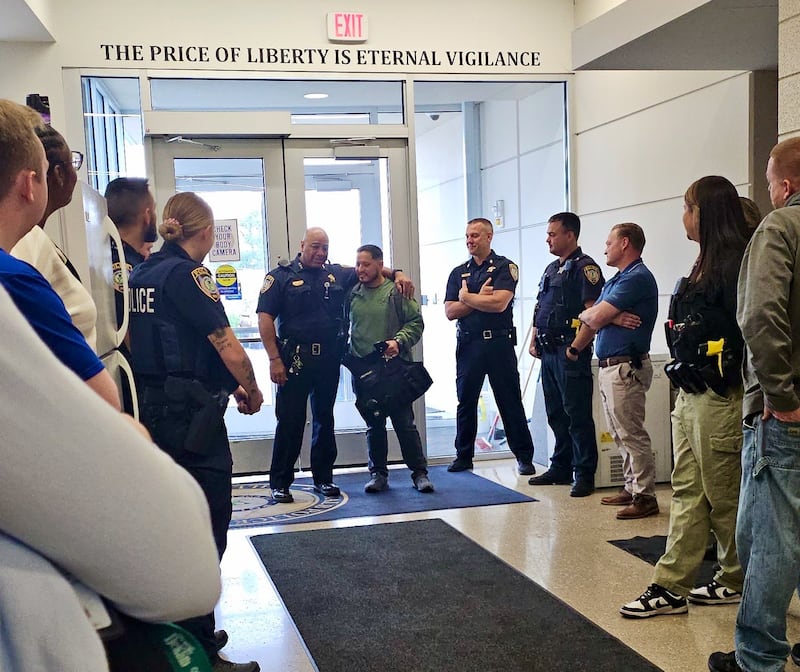 DeKalb police officer Jesus Rodriguez (middle right), gets a hug from Police Chief David Byrd (middle left) and a warm welcome back as he returned to work in DeKalb on May 28, 2025, following a yearlong U.S. Army deployment to Jordan.