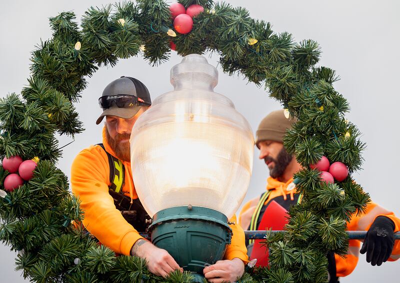 Austin Clark (left) and Steve Fassler wire up a wreath and bow Wednesday, Nov. 20, 2024, in downtown Dixon. The city will hold their annual Christmas Walk on Dec. 6.