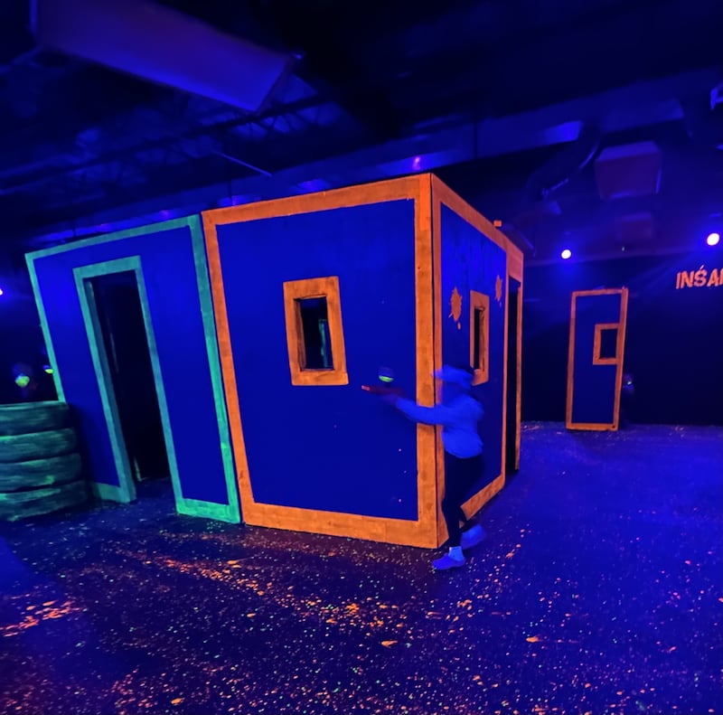 A player aims a battery-powered blaster during a game of GellyBall at Peru Mall. The game, recommended for ages 5 and up, features blacklight effects and allows players to participate in games such as capture the flag and freeze tag.