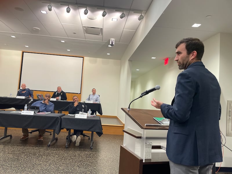 DeKalb City Engineer John Laskowski (right) approaches the City Council during its Oct. 13, 2025, meeting to provide some input on a proposed reconfiguration plan for the intersection at North First Street and Sycamore Road.