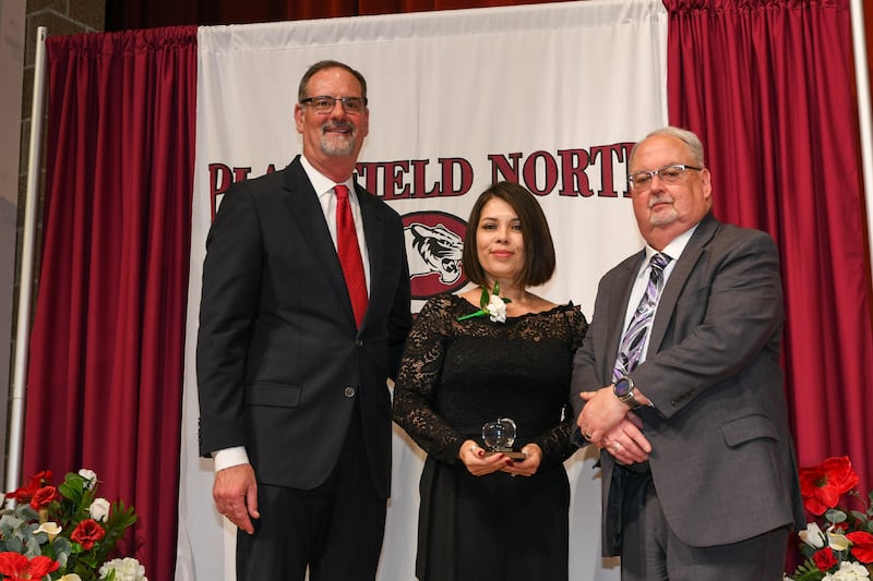 District 202 Superintendent of Schools Glenn Wood (left) and District 202 Board of Education President Rod Westfall (right) pose with Tina Vasquez, paraprofessional at Bonnie McBeth Early Learning Center, after she won an Award of Excellence during a ceremony on Thursday, April 9, 2026, in Plainfield.