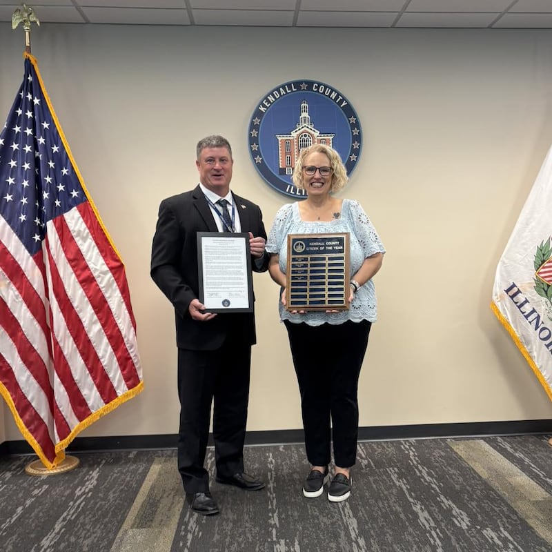 Kendall County Board Chairman Matt Kellogg, left, presents Oswego resident and former Kendall County Board member Robyn Vickers, right, with the 2026 Kendall County Citizen of the Year award.