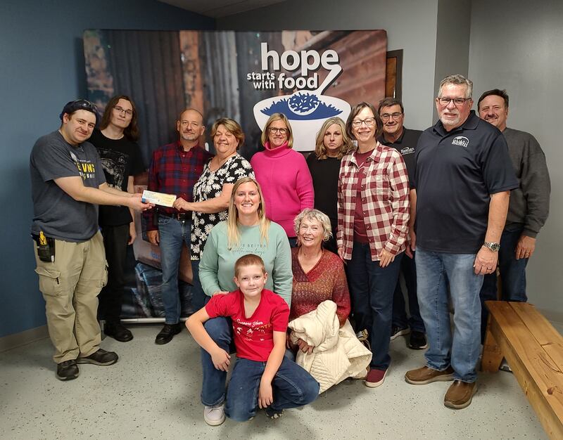 Pictured are the Plano Methodist Church volunteers—Nathan, Paul, Melanie, Nancy, Charmaine, Bonnie, Jim, Bill, Ken, Jordyn, Case, and Rose—presenting a check to the Feed My Starving Children manager.