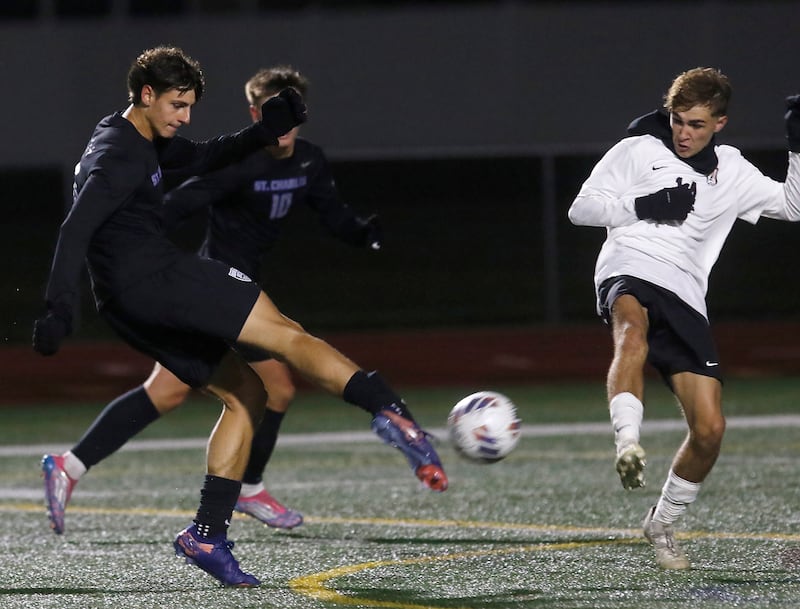St. Charles North's Dino Valenti shoots the ball at the goal as McHenry's Kyren Rivard defends during an IHSA Class 3A Huntley Regional boys soccer semifinal match on Tuesday, Oct. 21, 2025, at Huntley High School.