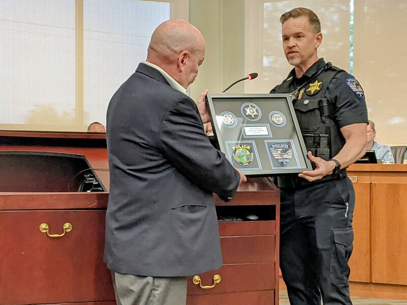 In honoring him for his 10 years of service on the Oswego Police Commission, Oswego Police Chief Jason Bastin presents  Ron Elvin with a shadow box during the May 27 Oswego Village Board meeting.