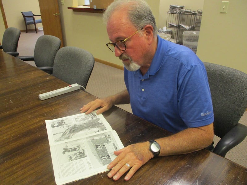 Retired Joliet firefighter Tim Carlin looks at a photo showing himself and volunteers treating a patient injured in the Plainfield tornado in the "Will County Winds of Fury" book produced by The Herald-News. Aug. 22, 2025