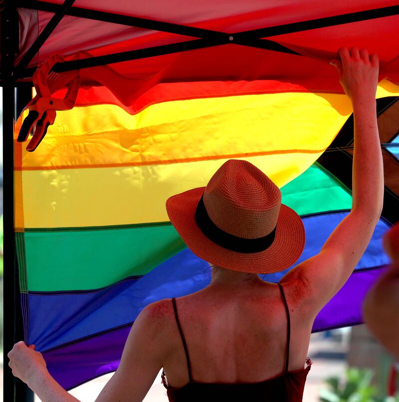 A vendor hangs a flag in her booth Saturday, June 21, 2025, during the DeKalb Pride Fest in front of the Egyptian Theatre in DeKalb.