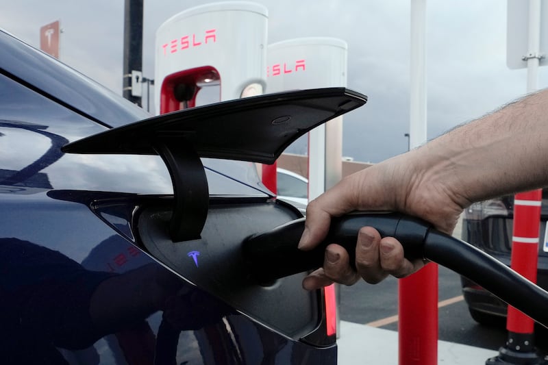 A motorist charges his electric vehicle at a Tesla Supercharger station in Detroit.