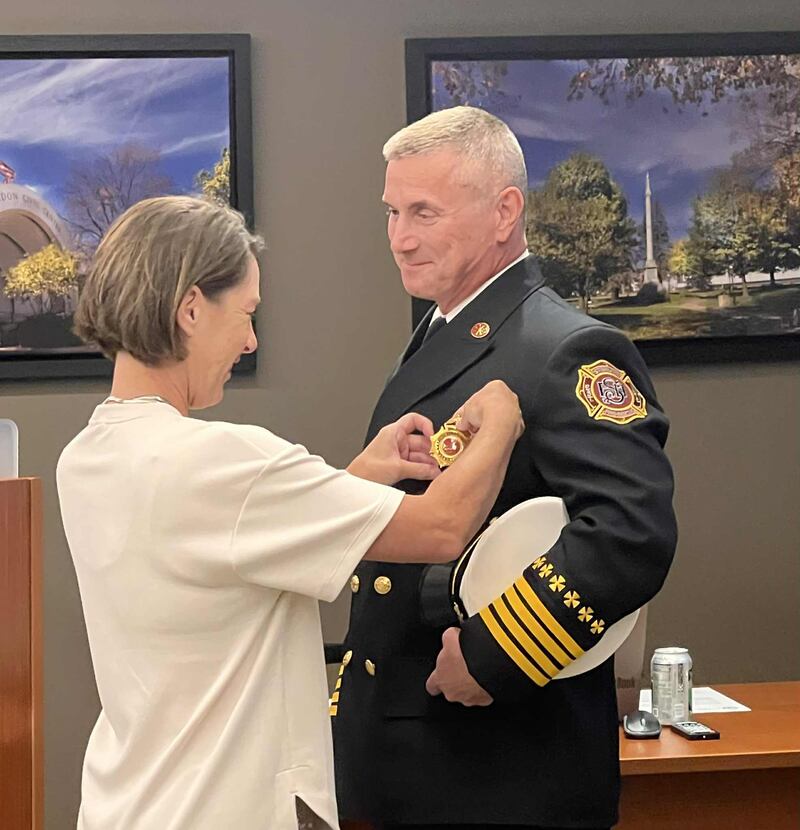Sheri Melton pins the badge on her husband, Scott Melton, during his swearing-in as deputy chief of the Sterling Fire Department at the City Council meeting on Sept. 2, 2025.