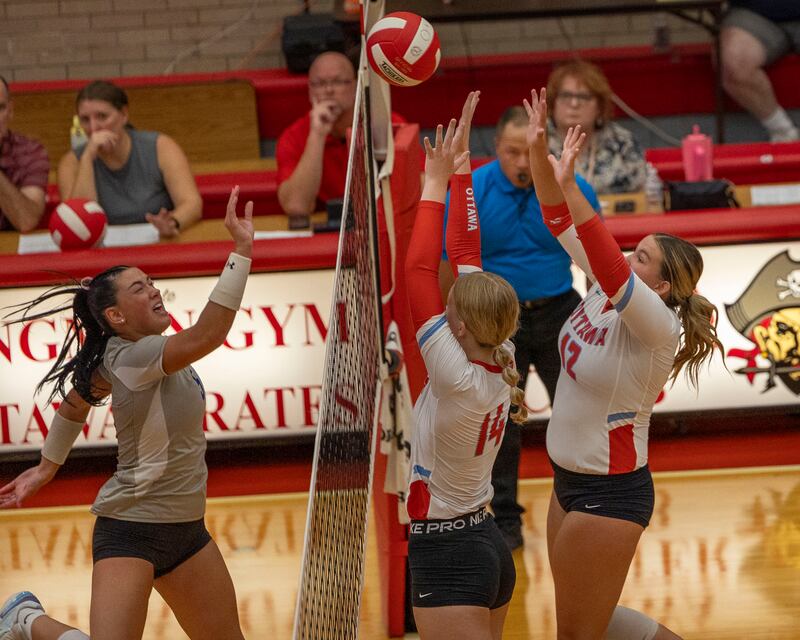 (from left) Keeley Lawson (5) of Princeton hits volleyball over net as Libby Muffler (14) of Ottawa and teammate Kerrigan Cooney (12) attempt to block on Thursday, Sept. 18, 2025 at Ottawa High School in Ottawa.