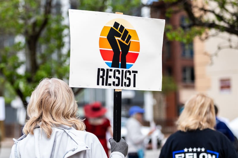 An attendee holds up a sign at the May Day Weekend Rally in Downtown Joliet on May 3, 2025.