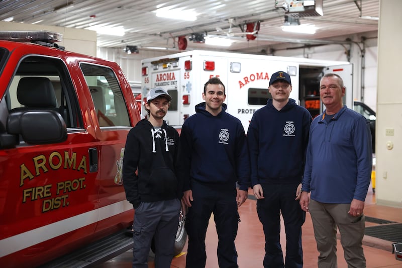 Aroma Fire Protection District Fire Chief Luke Shepherd, right, and firefighters, from left, Jeremy Neufeld, Andrew Bowes and Kyle King stand in the fire station on April 8, 2026. The four are part of a crew that responded immediately to the aftermath of the March 10 tornado that hit Aroma Township and Aroma Park.