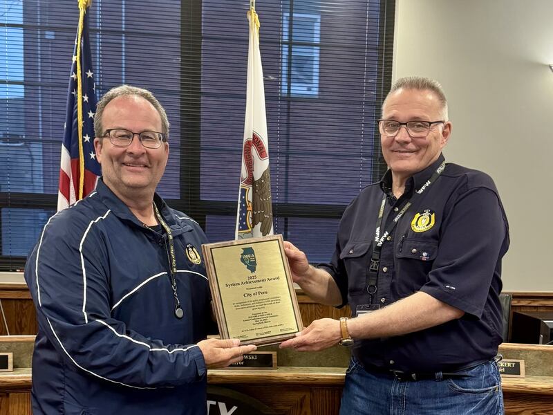 Peru Mayor Ken Kolowski and Electric Operations Manager Kevin Minnick hold the 2025 Illinois Municipal Utilities Association System Achievement Award.