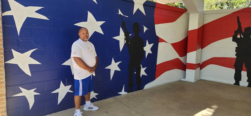 Artist Ozell Taylor poses beside the flag mural he did at Veterans Memorial Park in Rock Falls.