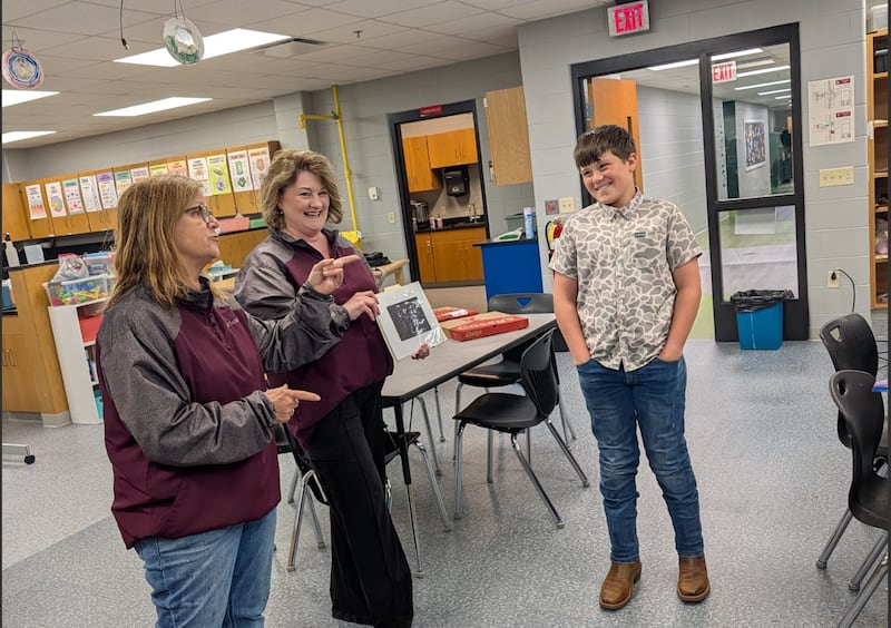 La Salle Parks and Recreation Director Lynda Kasik and Administrative Assistant Julie Gunia congratulate Atlee Turigliatti of Dimmick for winning the Celebration of Lights Student Display Contest with his picture of Santa Claus carrying a fishing pole.