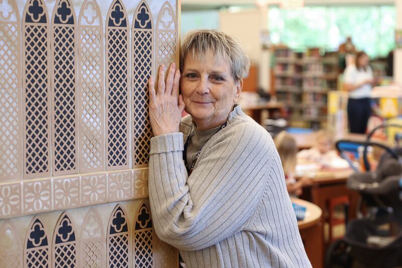 Jan Stack playfully hugs the Big Ben she crafted on display at the Joliet Public Library Black Road Branch for their Travel Through the Pages summer reading program on Thursday May 30, 2024 in Joliet.