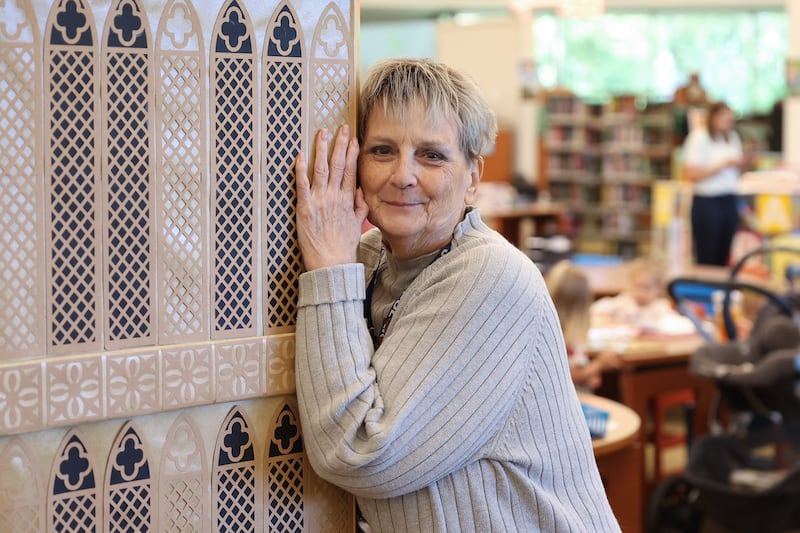 Jan Stack playfully hugs the Big Ben she crafted on display at the Joliet Public Library Black Road Branch for their Travel Through the Pages summer reading program on Thursday May 30, 2024 in Joliet.