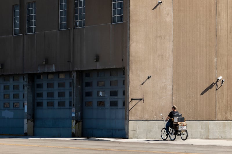 A cyclist rides past the former National Manufacturing building in Sterling Tuesday, Oct, 7, 2025. The building is situated in the designated River Edge Redevelopment Zone.