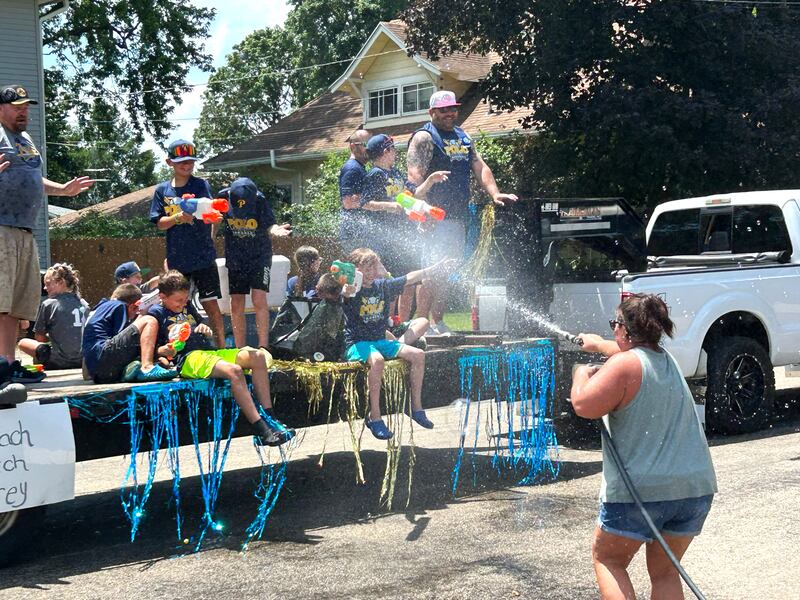 Billie Quaco sprays water at one of the youth baseball teams as they drive past her home during the Town & Country Days Parade on Sunday, June 29, 2025.