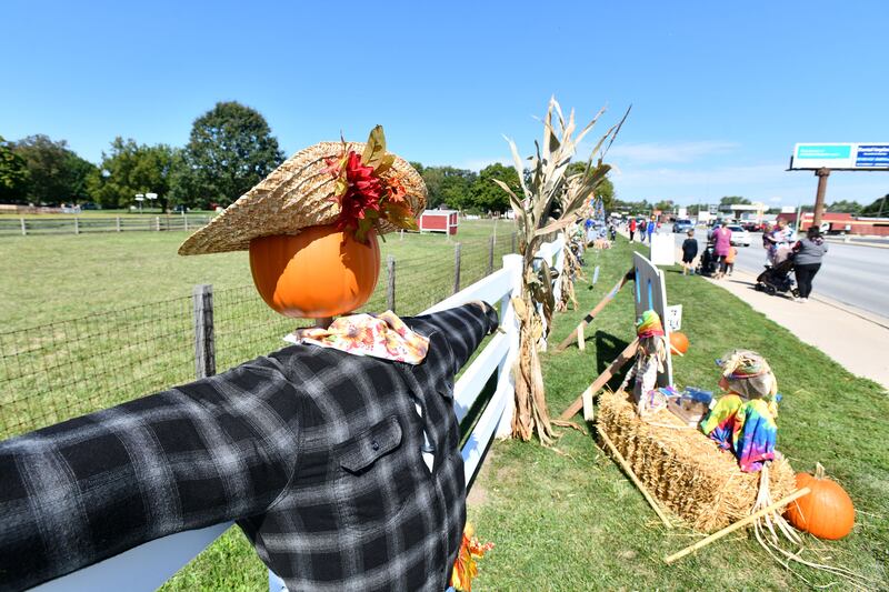 Dozens of decorated scarecrows line the fence at Perry Farm Park for the annual Scarecrow Festival in 2022 as attendees stroll along Kennedy Drive in Bradley.