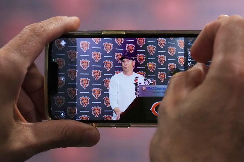 A reporter takes photos of Chicago Bears head coach Ben Johnson during a news conference after practice at NFL football minicamp at Halas Hall in Lake Forest, Ill., Tuesday, June 10, 2025. (AP Photo/Nam Y. Huh)
