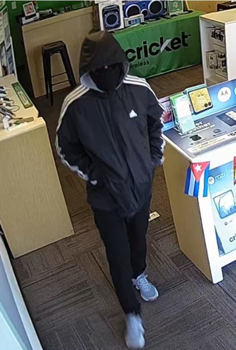 Joliet police are looking for the suspect shown in this photograph who police say is linked to a robbery that occurred on Saturday, Feb. 7, 2026. The suspect is described as a male, approximately 5'6"–5'7" tall with a skinny build and short brown curly hair. He was wearing a gray and black Adidas hoodie, black jogger pants, blue tennis shoes, black sunglasses, and a black neck gaiter used to conceal his face.