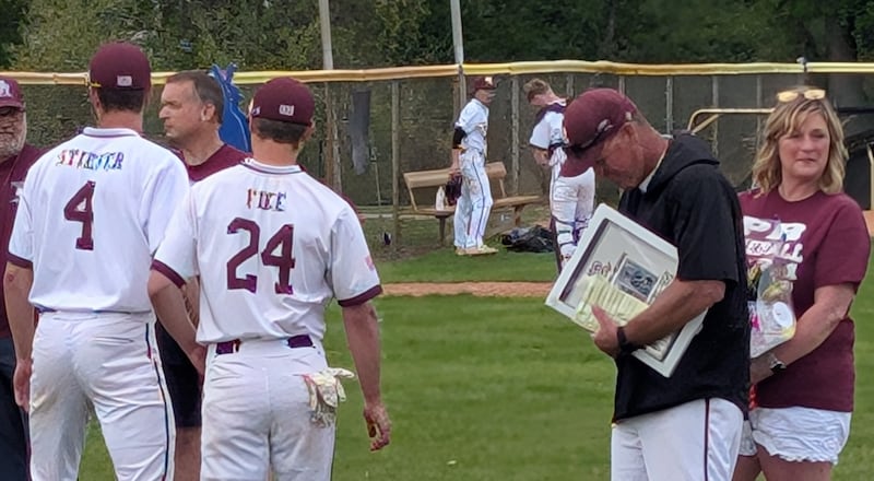 Prairie Ridge baseball coach Glen Pecoraro receives a jar of infield dirt from his players Karson Stiefer and Christopher Fike before the Wolves' game against Crystal Lake Central on Monday, May 12, 2025, in Crystal Lake. Pecoraro, whose wife, Beth, is standing next to him, is retiring from coaching after this season.