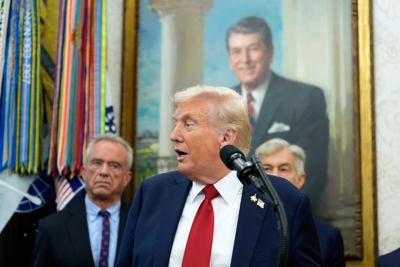 President Donald Trump speaks in the Oval Office of the White House, Tuesday, Sept. 30, 2025, in Washington. Behind the President are Secretary of Health and Human Services Robert F. Kennedy, Jr., left, and Mehmet Oz, Administrator for the Centers for Medicare & Medicaid Services. (AP Photo/Alex Brandon)