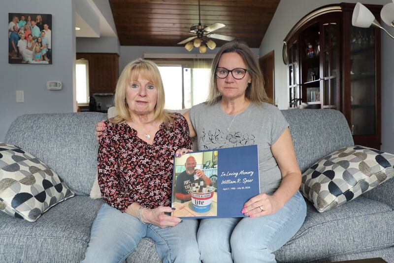 Boni Speer, left, and her daughter, Tracy Balhan, hold a photo of Bill Speer, Tracy’s father, in Aurora, Ill., on Friday, March 14, 2025. (Benjamin Thorp/WFYI Public Media via AP)
