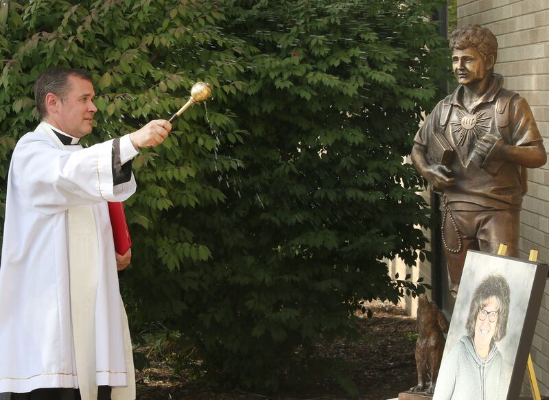 Father Paul Carlson, blesses a newly unveiled a new statue of St. Carlo Acutis outside on Wednesday, Sept 10, 2025 at the St. Carlo Acutis school in Oglesby. The statue is in honor of Mary Happ who taught for 29 years at Holy Family School.